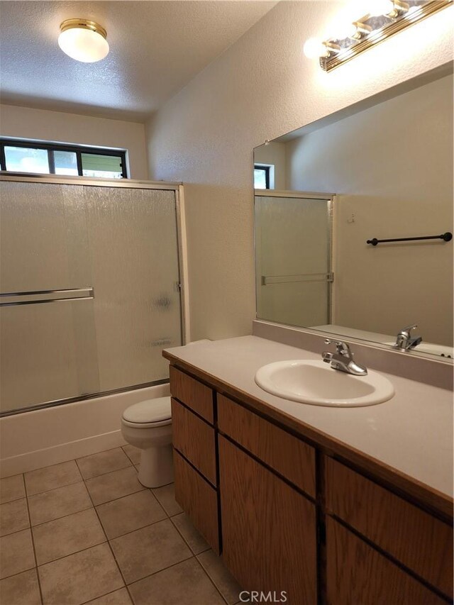 18580 Paskenta Rd, Corning, CA 96021 - bathroom with vanity, toilet, bath / shower combo with glass door, a textured ceiling, and tile patterned floors