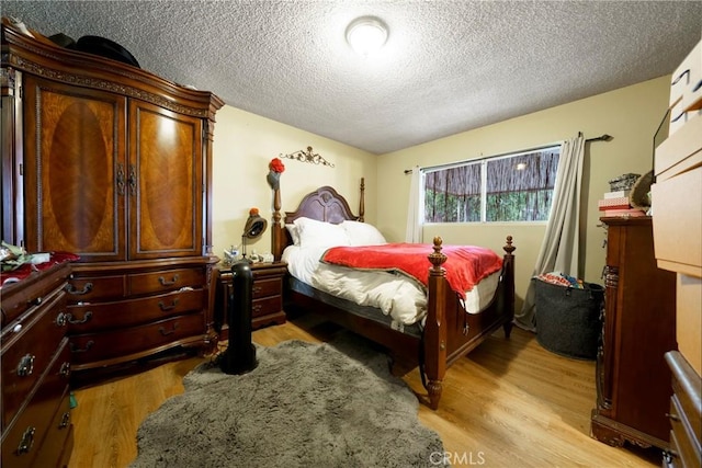 bedroom featuring a textured ceiling and light wood finished floors