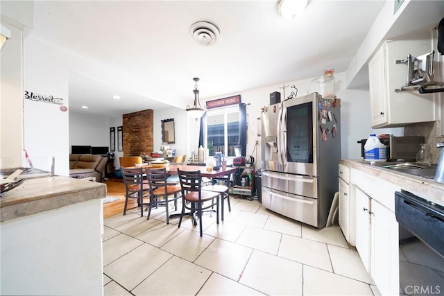 kitchen featuring white cabinets, stainless steel fridge, light countertops, black dishwasher, and light tile patterned floors