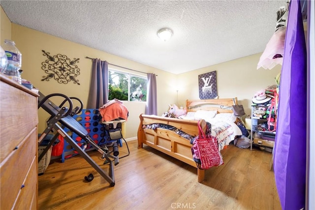 bedroom with a textured ceiling and wood finished floors