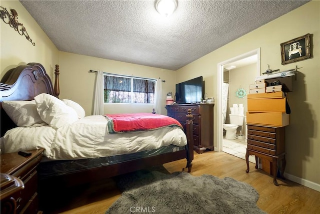 bedroom featuring ensuite bathroom, light wood-type flooring, and a textured ceiling