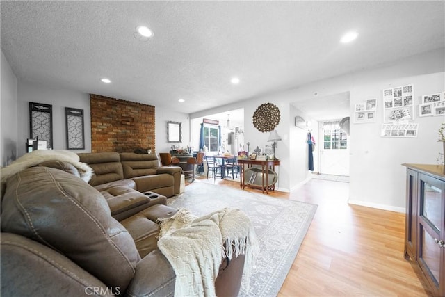 living room with light wood-style floors, baseboards, recessed lighting, and a textured ceiling