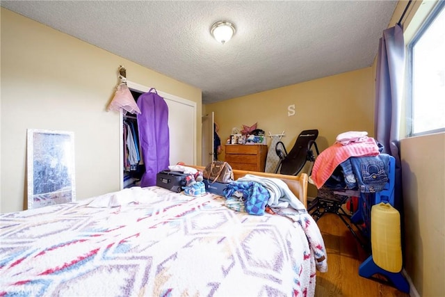 bedroom with a textured ceiling and wood finished floors