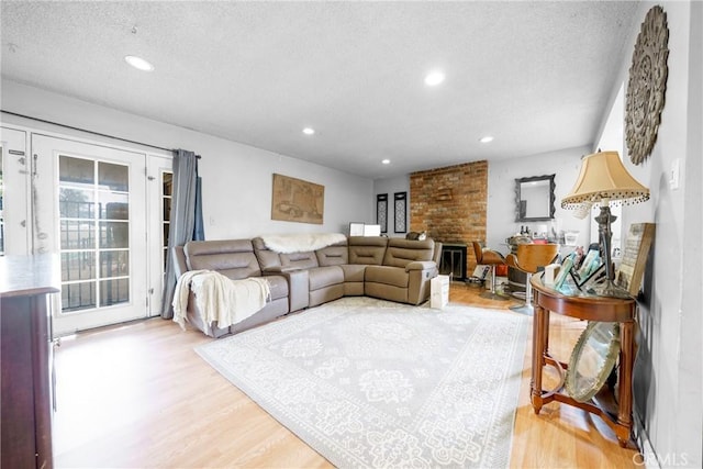 living area with recessed lighting, light wood-style flooring, a textured ceiling, and a healthy amount of sunlight