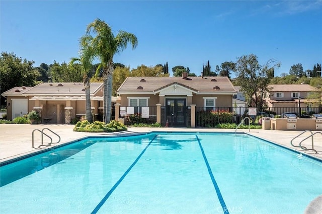 community pool with fence, a patio, and french doors