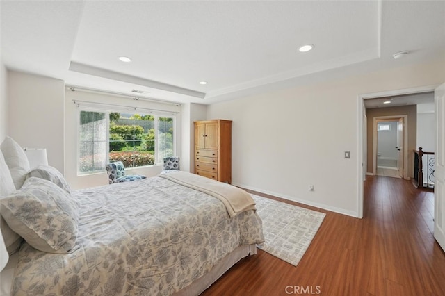 bedroom featuring a tray ceiling, recessed lighting, and wood finished floors