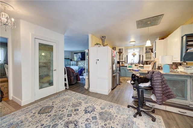 home office featuring light wood-type flooring, a chandelier, and baseboards