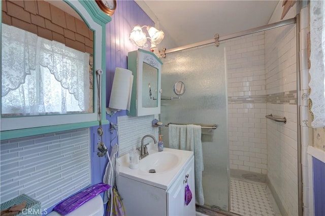 bathroom with a shower stall, vanity, and backsplash