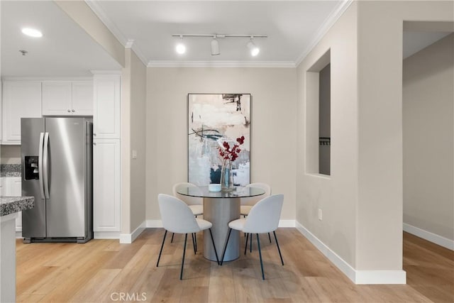 dining room with track lighting, baseboards, ornamental molding, and light wood-style flooring
