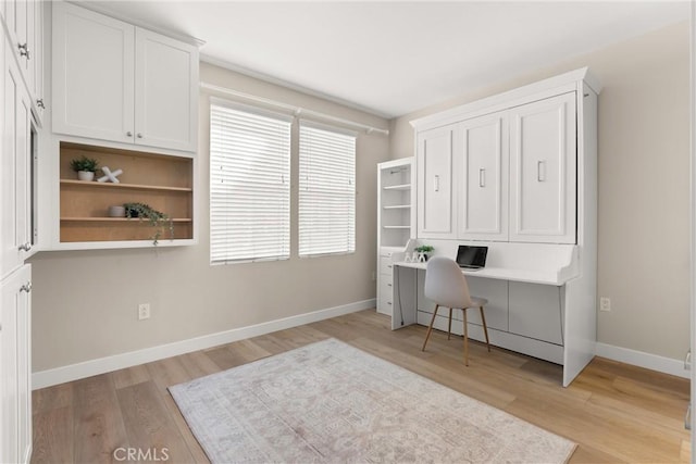 office with built in study area, baseboards, and light wood-type flooring