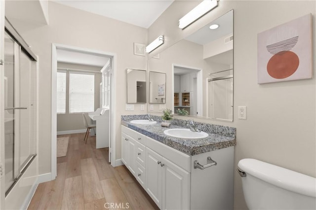 bathroom featuring a sink, a stall shower, toilet, and wood finished floors