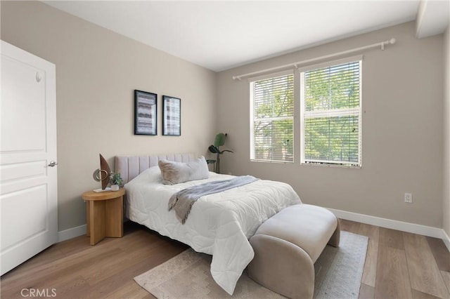 bedroom with baseboards and light wood finished floors