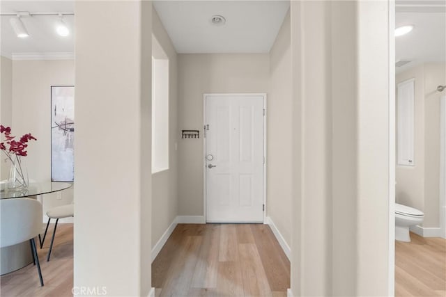 hallway featuring track lighting, baseboards, and wood finished floors
