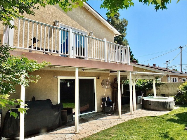 back of house with a patio, stucco siding, a hot tub, and a deck