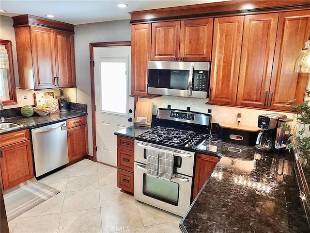 kitchen with a sink, dark stone counters, brown cabinetry, and stainless steel appliances