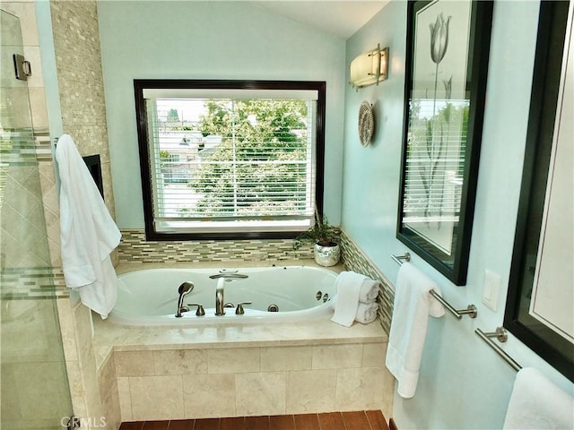 full bathroom with a whirlpool tub, tiled shower, and lofted ceiling