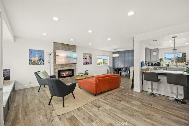 living area featuring recessed lighting, light wood-style flooring, baseboards, and a fireplace