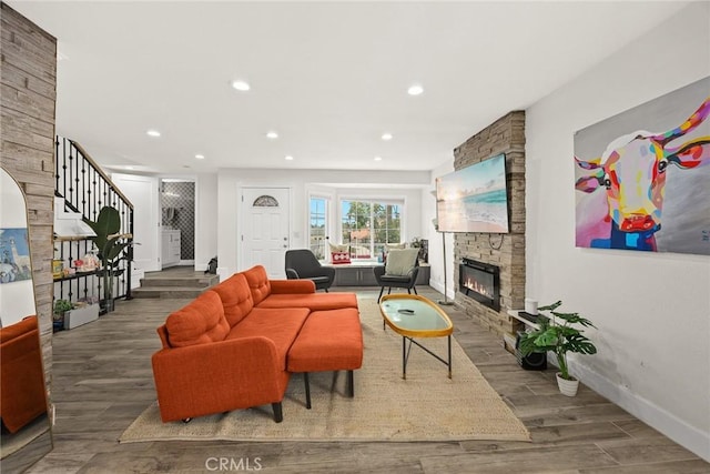living area featuring baseboards, recessed lighting, a stone fireplace, and wood finished floors