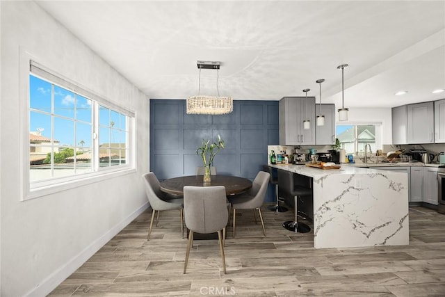 dining room featuring light wood-style floors, baseboards, a decorative wall, and recessed lighting