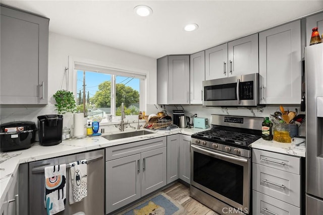 kitchen with recessed lighting, a sink, gray cabinets, and appliances with stainless steel finishes