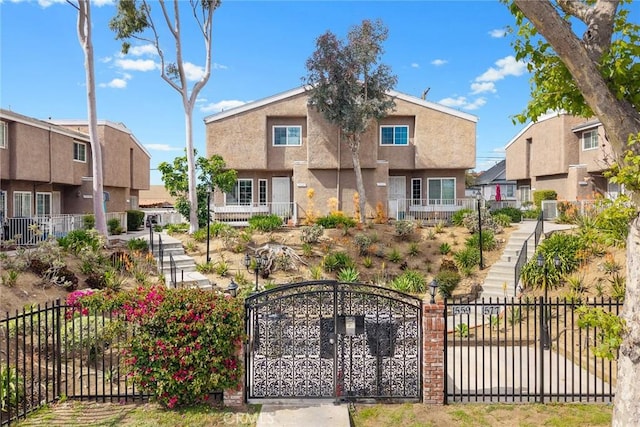 view of front of house featuring a residential view, a gate, fence private yard, and stucco siding