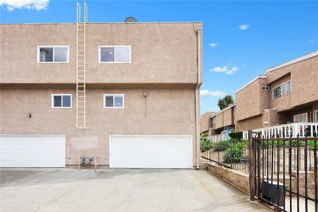 exterior space featuring a garage, fence, and stucco siding