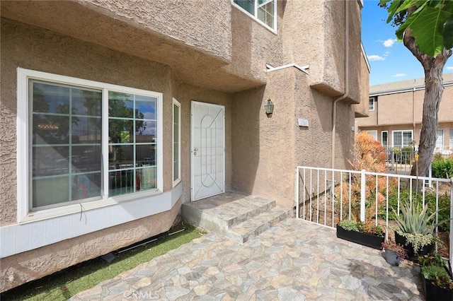 property entrance with fence and stucco siding