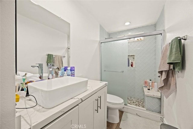 full bathroom featuring vanity, toilet, wood finished floors, and a stall shower