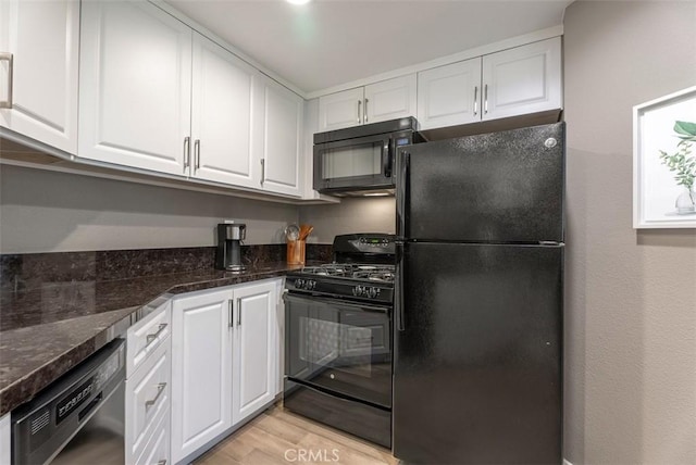 kitchen with white cabinetry, light wood finished floors, black appliances, and dark stone countertops