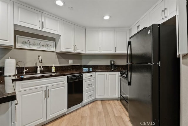 kitchen featuring white cabinets, a sink, recessed lighting, light wood-type flooring, and black appliances