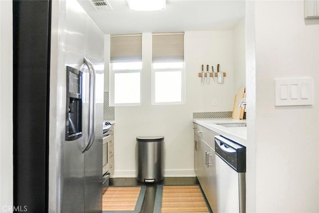 kitchen with light countertops, dark wood-type flooring, stainless steel refrigerator with ice dispenser, visible vents, and dishwashing machine