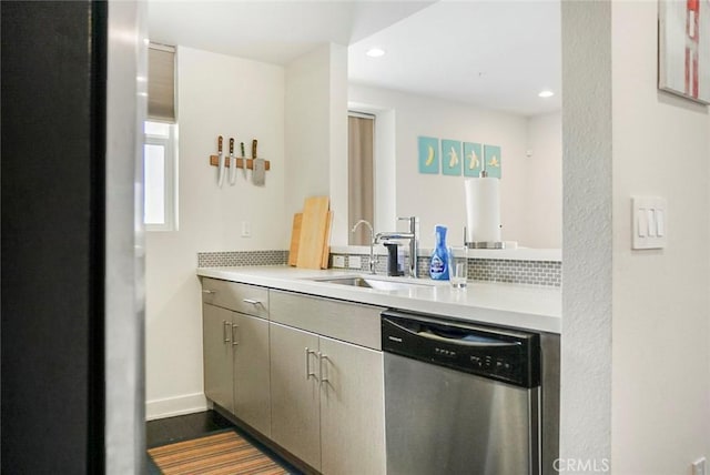kitchen featuring backsplash, dishwasher, a sink, light countertops, and recessed lighting