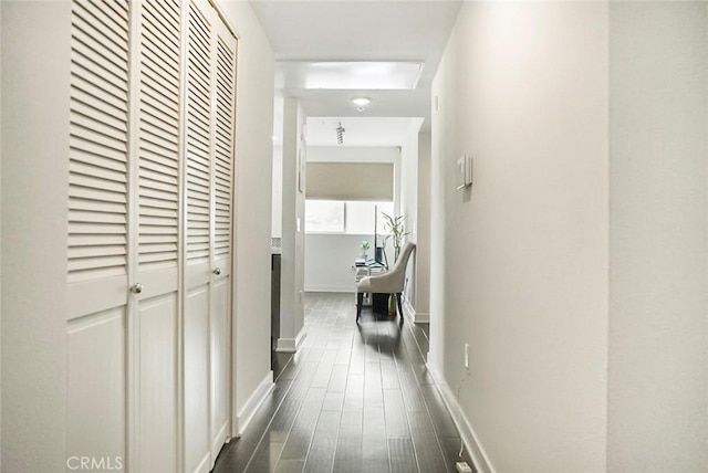 hall with dark wood-style flooring and baseboards