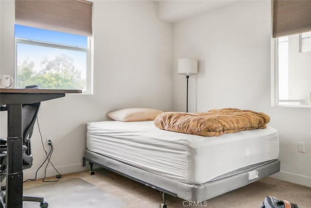 carpeted bedroom with baseboards and multiple windows