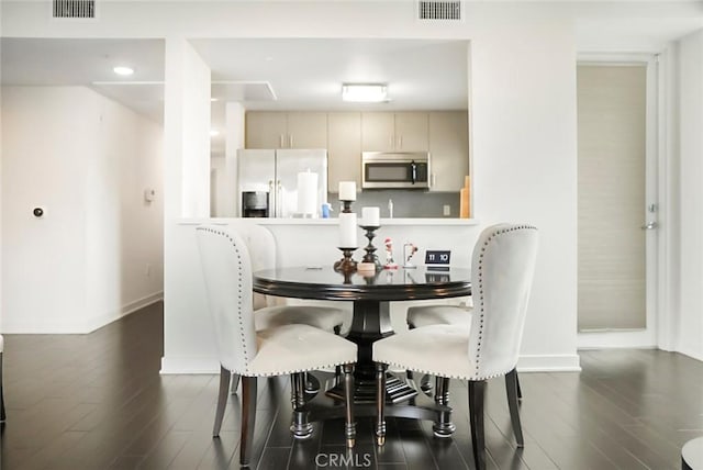 dining space with baseboards, wood finished floors, and visible vents