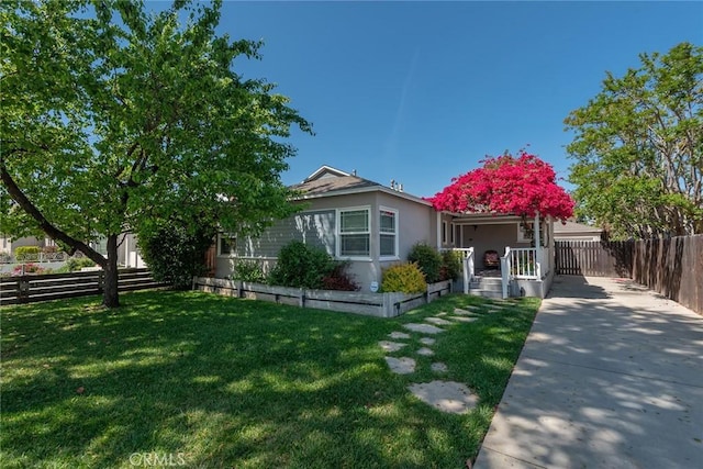 view of front of home with stucco siding, a front lawn, fence, and covered porch