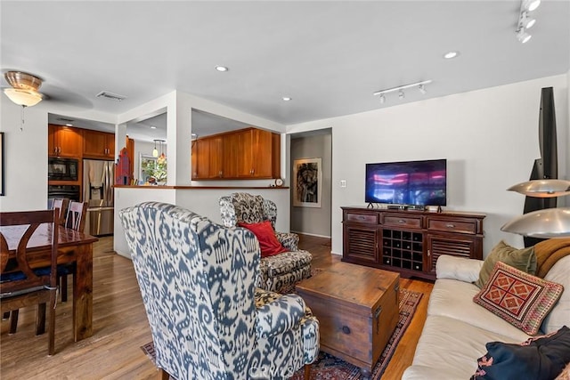 living room with track lighting, light wood-style flooring, and visible vents