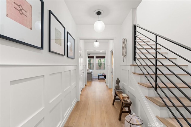 112 Gemstone, Irvine, CA 92620 - corridor featuring a wainscoted wall, a decorative wall, stairs, and light wood-style flooring