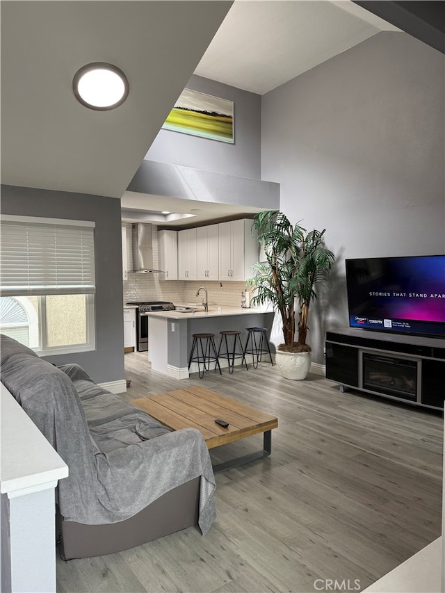 living room featuring baseboards, light wood finished floors, and vaulted ceiling