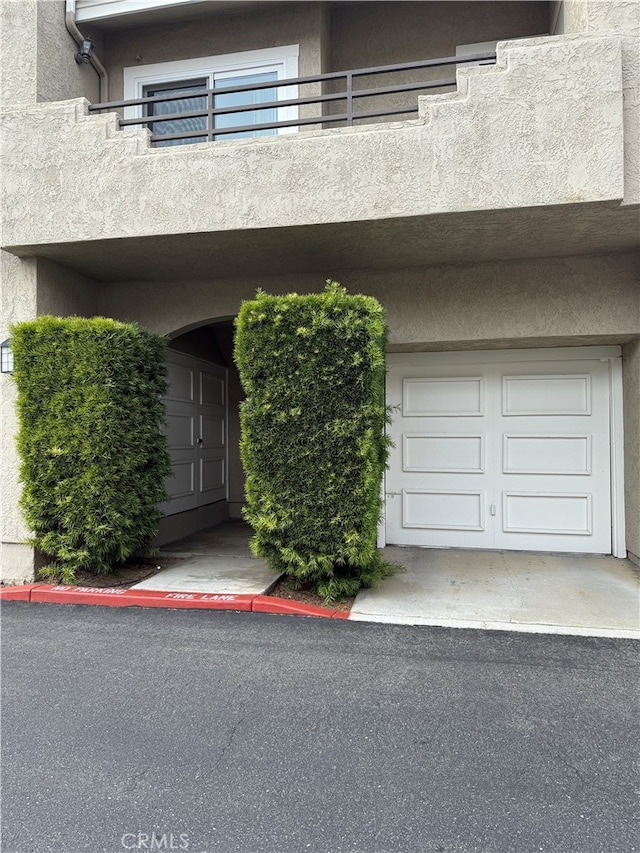 property entrance with a garage, stucco siding, and a balcony