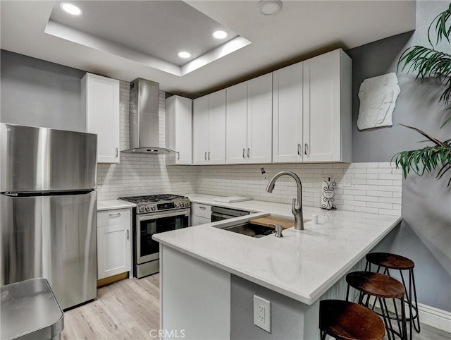 25081 Leucadia St Unit F, Laguna Niguel, CA 92677 - kitchen featuring appliances with stainless steel finishes, wall chimney exhaust hood, a sink, light wood-style flooring, and recessed lighting