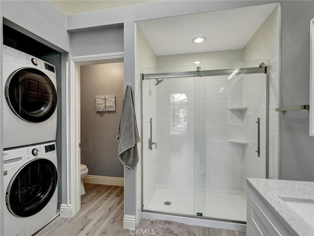 25081 Leucadia St Unit F, Laguna Niguel, CA 92677 - bathroom featuring estacked washer and dryer, toilet, wood finished floors, a stall shower, and baseboards