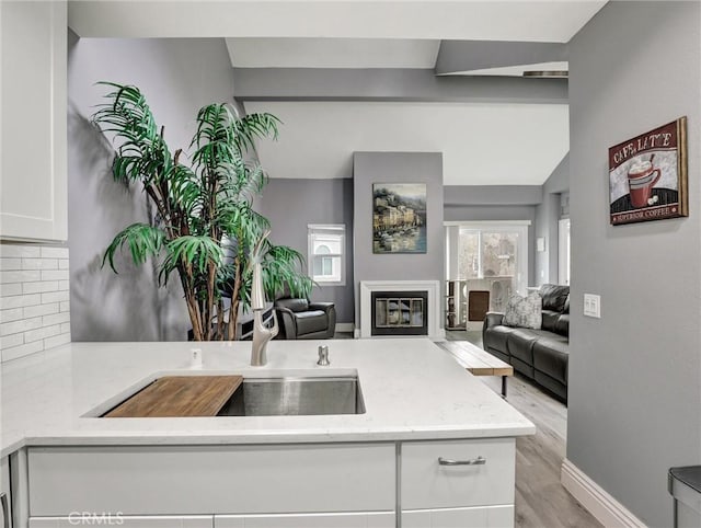 25081 Leucadia St Unit F, Laguna Niguel, CA 92677 - kitchen featuring open floor plan, tasteful backsplash, white cabinets, a sink, and light wood-style floors