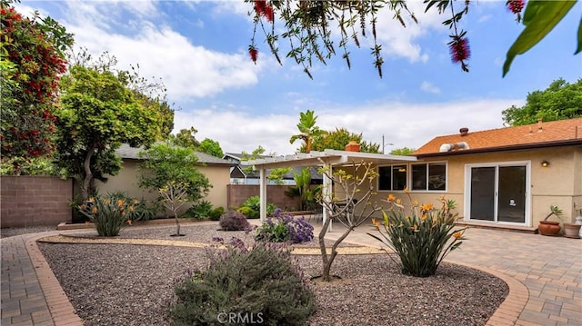 back of property with a patio area, stucco siding, a pergola, and fence