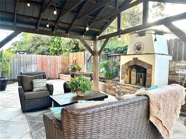 view of patio featuring fence, an outdoor living space with a fireplace, and a gazebo