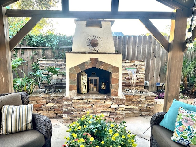 view of patio featuring exterior fireplace and fence