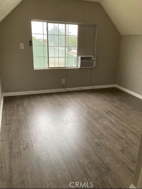 2404 E California, Bakersfield, CA 93307 - additional living space featuring wood finished floors, healthy amount of natural light, vaulted ceiling, baseboards, and cooling unit