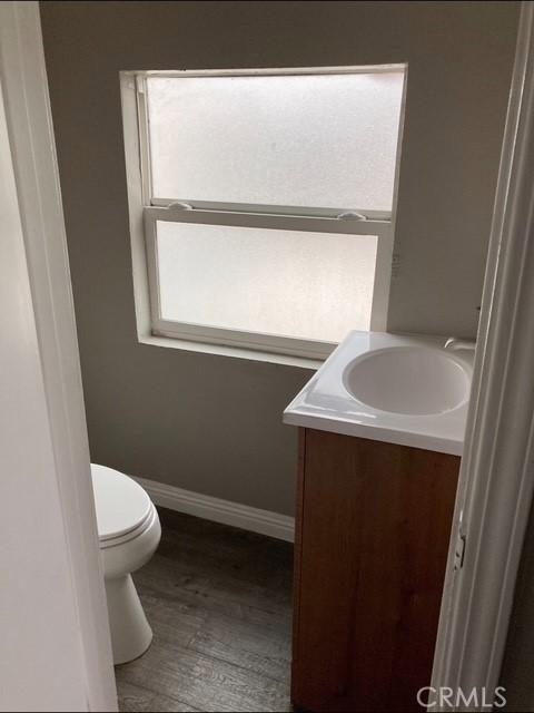 2404 E California, Bakersfield, CA 93307 - half bathroom with vanity, baseboards, toilet, and wood finished floors