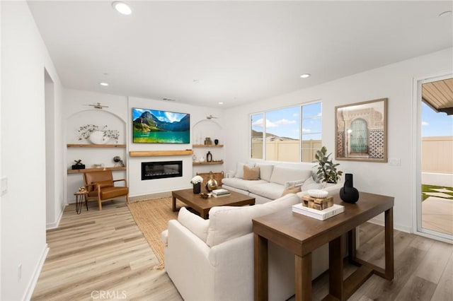 31768 Constellation Dr, Menifee, CA 92586 - living room with light wood finished floors, a glass covered fireplace, recessed lighting, and baseboards