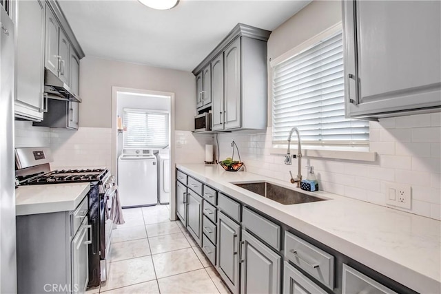 10005 Elwood Ave, Fontana, CA 92335 - kitchen featuring a sink, washing machine and clothes dryer, under cabinet range hood, gray cabinetry, and appliances with stainless steel finishes